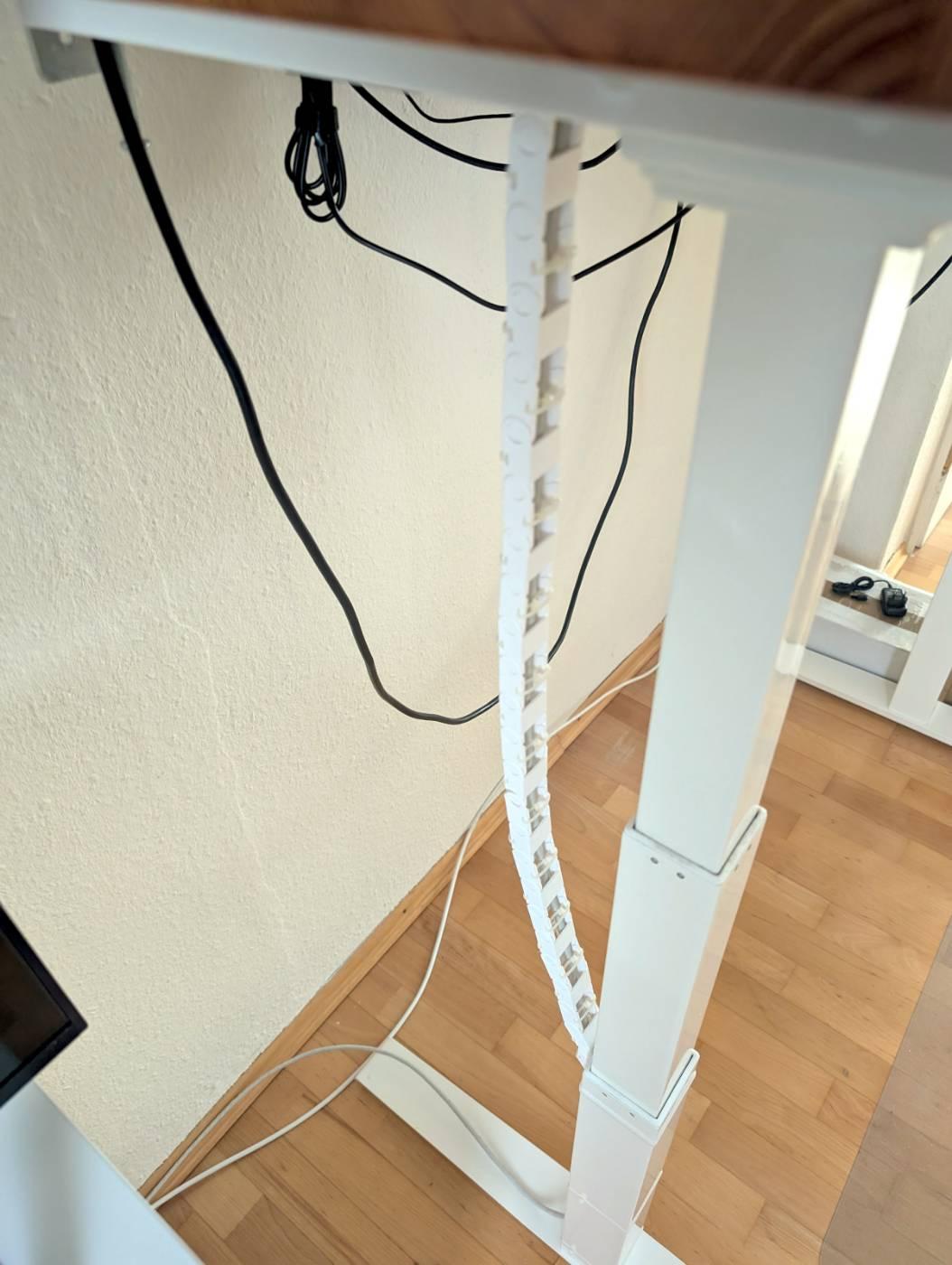 The desk is in a high position. The chain runs parallel to the telescopic table leg.

The cable chain is nearly taut and the cable is still protected inside.